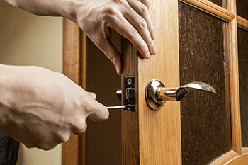 Handyman repairing a brass door handle/lock during general home maintenance service